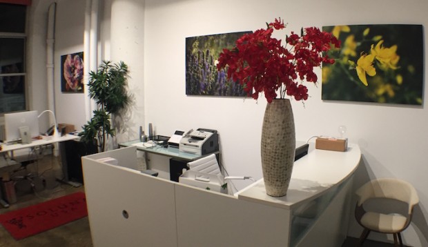 Front desk area of Innovative Medicine Headquarters. White desks, chairs and furniture with red accents and colorful nature canvas prints were utilized to enhance productivity.
